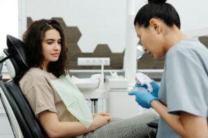 歯科医院で患者に丁寧に説明を行う歯科医師と診療チェアに座る女性