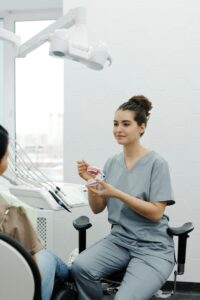 歯科医院で患者に口腔模型を使って説明する歯科医師